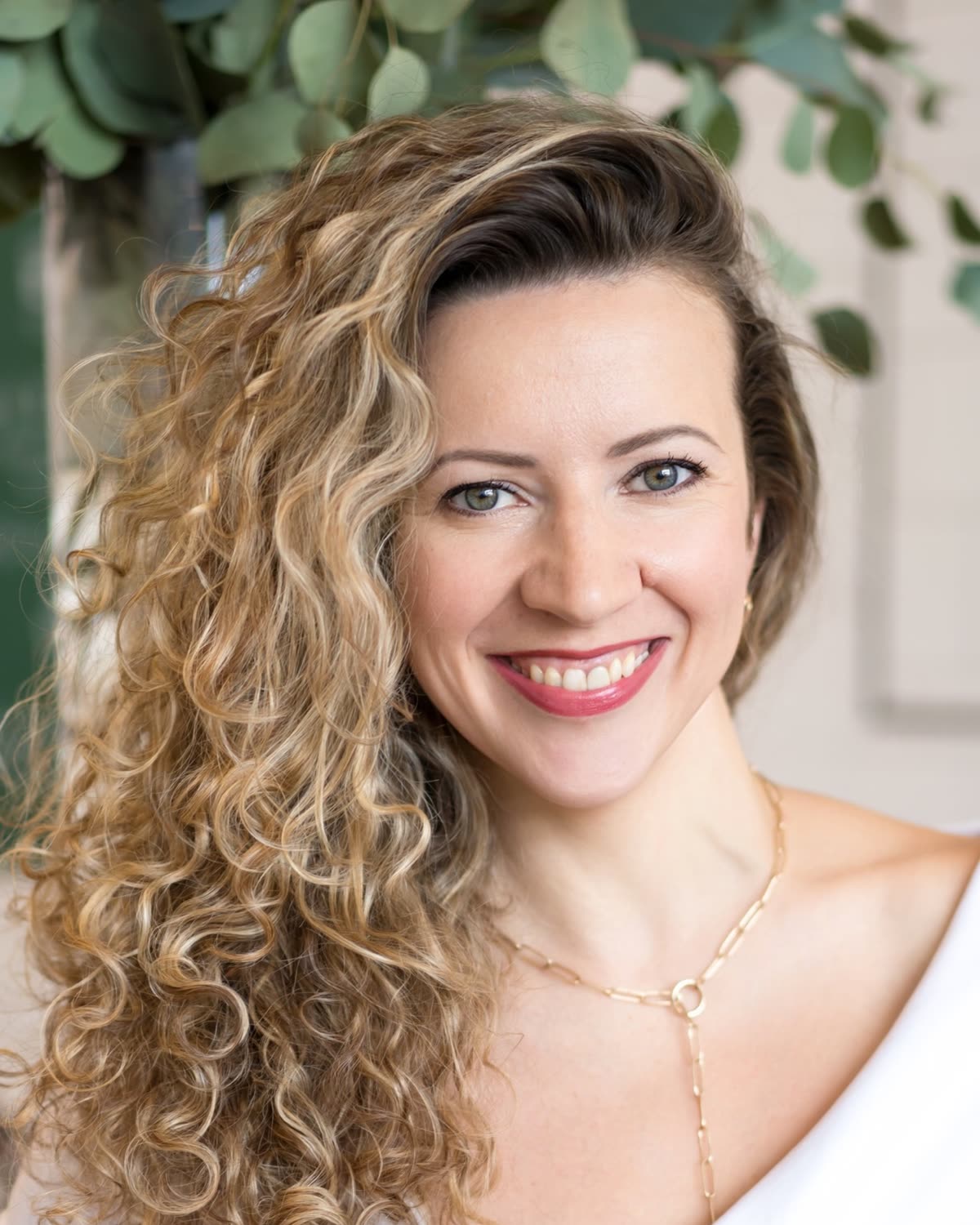 Portrait of Nadia, smiling, with eucalyptus behind her