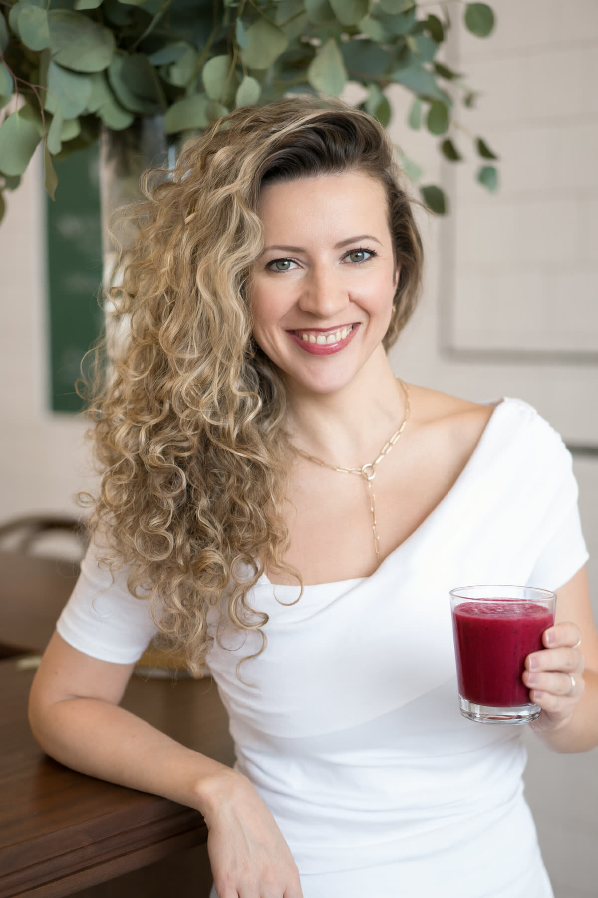 Nadia smiling, holding a glass of berry smoothie